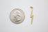 A gold lightning bolt charm rests next to a US quarter coin to show its scale.