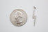 A sparkling pavé diamond lightning bolt pendant rests next to a US quarter coin for scale.