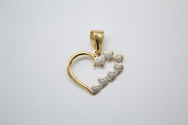 A delicate two-tone gold heart pendant features a smooth yellow gold outline accented with a cascade of textured white gold miniature hearts.