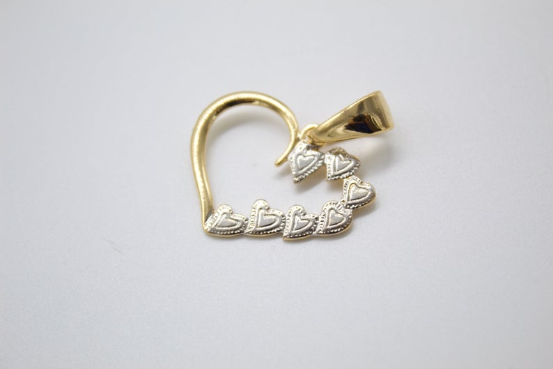 A two-tone gold heart pendant features an open gold outline accented with a line of small textured hearts.