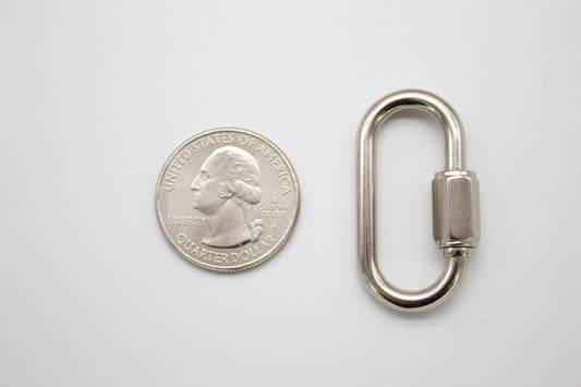 A shiny silver quick link sits next to a US quarter coin on a white surface to show its size.