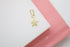 A sparkling gold star pendant rests delicately on a white and pink display stand.