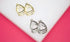 Two pairs of textured, openwork triangle stud earrings display in gleaming gold and silver tones on a white and pink background.