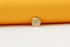 A shiny gold coin pendant featuring embossed star details rests against a vibrant yellow and white background.