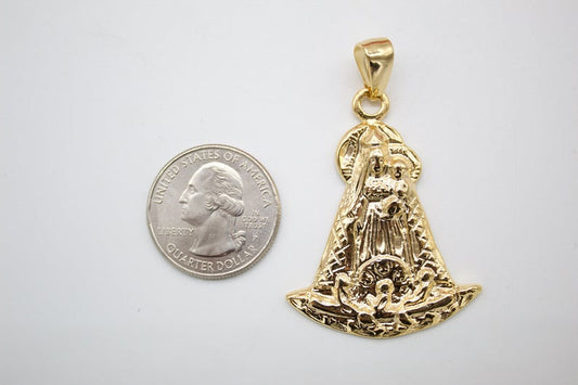 A detailed gold pendant of the Virgin of El Cisne rests beside a US quarter for scale.
