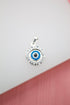A silver evil eye pendant features a blue and white glass amulet surrounded by an ornate frame.