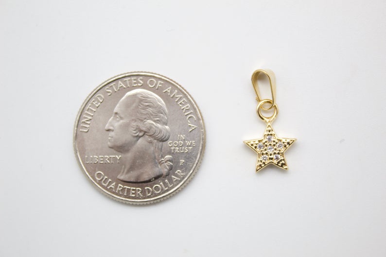 A small gold star pendant rests beside a US quarter for scale.