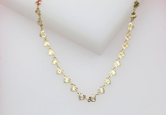 A delicate gold heart-link necklace rests gracefully against a soft white background.