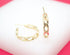 A pair of gold chain-link hoop earrings rests on a white display surface.