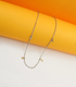 A delicate silver chain necklace featuring multiple dangling star charms rests against a vibrant yellow and white background.