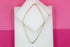 A delicate gold-plated heart-link chain necklace rests elegantly on white display blocks against a vibrant pink background.