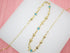 A delicate gold chain necklace sparkles with alternating blue star charms and metallic beads against a white display surface.