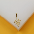 A delicate gold pendant shaped like a leafy twig, accented with small cubic zirconia stones, rests against a white and yellow display surface.