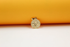 A gold pendant featuring a circular medallion with embossed sea life motifs, including a starfish, turtle, and seashells, rests against a vibrant yellow and white background.