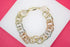 A tri-color gold chain link bracelet rests on a white and pink surface.