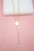 A delicate gold rosary necklace rests against a soft pink background, featuring shiny beaded links and a detailed crucifix pendant.