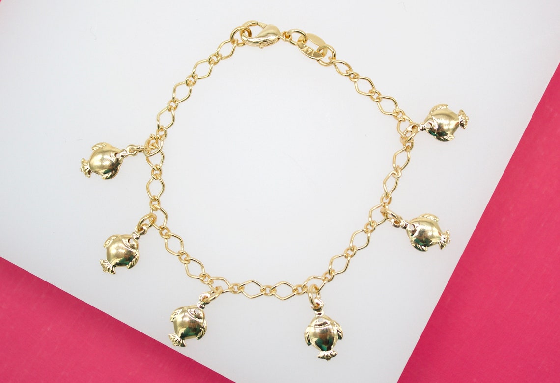 A delicate gold chain bracelet features five polished fish charms dangling from its links.