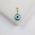 A gold evil eye pendant rests on a clean white surface, featuring vibrant blue and white enamel circles with a central black pupil.