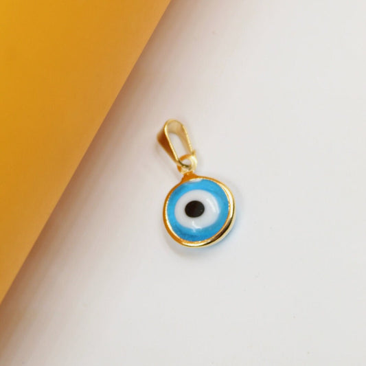 A gold-trimmed evil eye pendant rests against a split white and yellow background.
