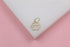 A sparkling gold paw print pendant rests on a white display against a soft pink background.