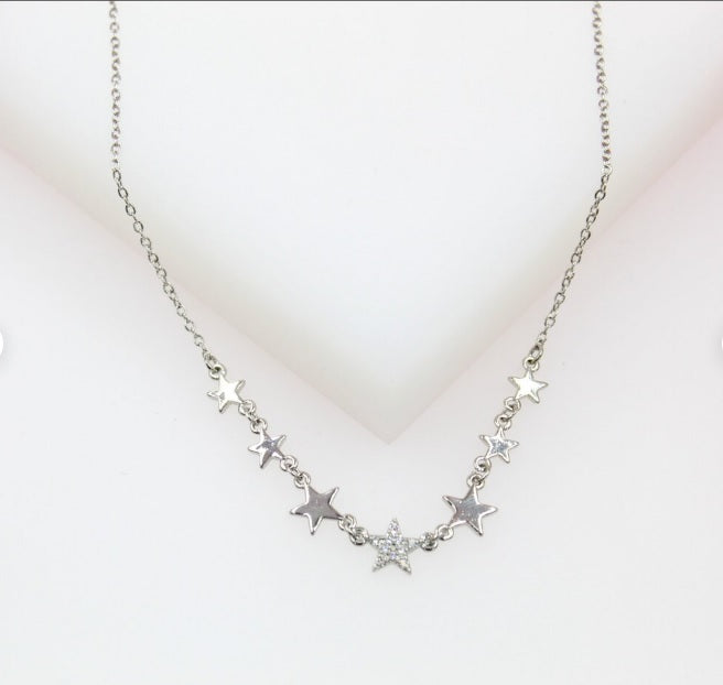 A delicate silver star pendant necklace rests against a neutral white background.