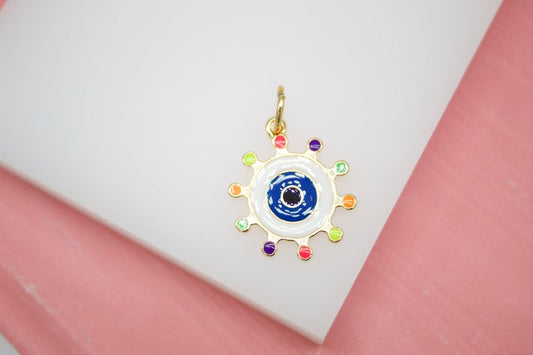 A gold evil eye charm featuring colorful enamel details rests on a white display surface.