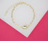 A delicate gold chain bracelet features an interlocking paperclip design and a polished heart charm, displayed against a dual-toned white and pink background.