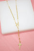 A gold rosary necklace with beaded chains and a crucifix pendant rests on a white display block.