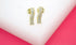 A pair of elegant gold wave stud earrings embellished with sparkling cubic zirconia stones rests on a white and pink display stand.