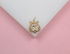 A gold tiger pendant embellished with sparkling pave crystals rests on a white and pink display surface.