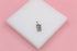 A silver rectangular Aquarius zodiac pendant rests on a white block against a pink background.