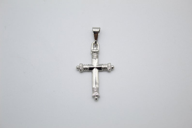 A polished silver cross pendant featuring decorative ribbed ends hangs centered against a plain light gray background.