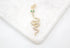 A sparkling gold snake pendant with diamond pave and green emerald eyes rests on a white marble surface.
