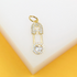 A gold safety pin pendant encrusted with sparkling cubic zirconia stones rests against a white and yellow background.