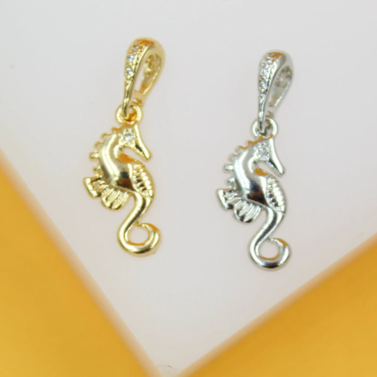 Two sparkling seahorse charms, one in gold and one in silver, rest side by side on a display surface.