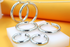 An assortment of thick silver hoop earrings in varying sizes sits on a white display block against an orange backdrop.