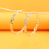 Two shiny gold chain link hoop earrings hang gracefully from a thin stick against a vibrant yellow background.