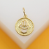 A gold Hamsa hand charm rests on a light surface, featuring an intricate evil eye design at its center.