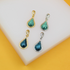 Four teardrop-shaped turquoise gemstone pendants in gold and silver settings rest on a white display surface.