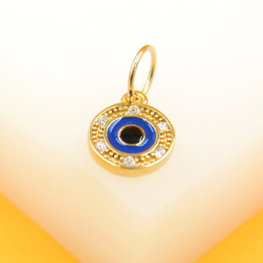 A gold evil eye pendant features a blue enamel center surrounded by sparkling cubic zirconia stones.