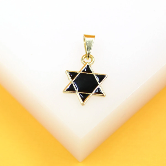 A gold Star of David pendant featuring black enamel rests on a white and yellow display surface.