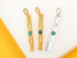 Three rectangular metal pendant charms, two in gold finish and one in silver, display cut-out arrow motifs accented with round turquoise stones.