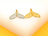 A silver and a gold whale tail charm rest side by side on a bright surface.