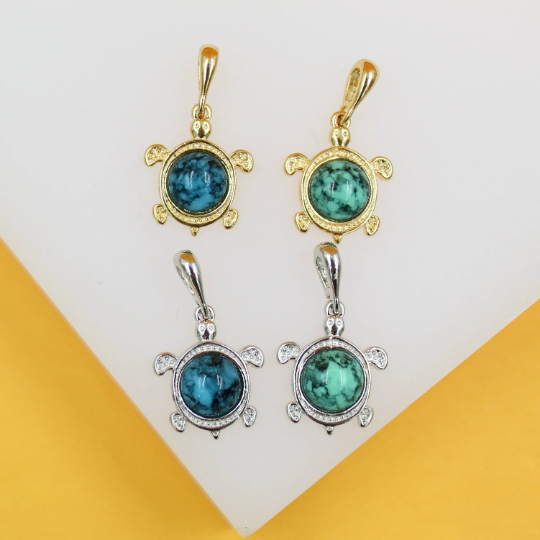 Four gold and silver turtle pendants feature vibrant turquoise stone shells against a clean white background.