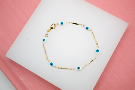 A delicate gold chain bracelet features alternating evil eye charms on a white display surface.