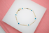 A delicate gold chain bracelet features alternating evil eye charms on a white display surface.
