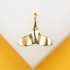 A shiny gold whale tail pendant rests against a white and yellow display background.