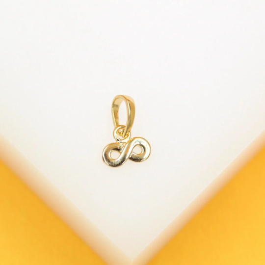 A small gold infinity symbol pendant rests on a minimalist white and yellow display stand.