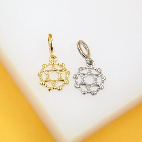 A gold and a silver Star of David pendant rest side by side on a white and yellow surface.