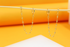 Two delicate gold double-piercing chain earrings hang from a wooden stick against a bright orange and white background.
